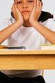 42-15471760 - Bored eleven year old girl sitting at desk, close-up, part of