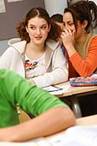 42-15516238 - Female teenager whispering with another one in classroom